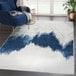 An Abani Atlas Collection blue and gray rug with an abstract mountain pattern in a room with a blue chair and a potted plant.