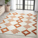 An orange and cream geometric tribal area rug on the floor.