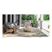 A Couristan light brown and ivory checkered area rug on a patio with a table and chairs on it.