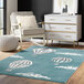 A blue Abani Play Collection area rug with hot air balloons on it on the floor next to a white dresser.