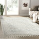 An Abani Cabo Collection cream and gray area rug with tasseled borders and fringes on the floor in a room.