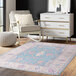 An Abani Molana Collection pink and blue area rug with floral designs on the floor in a room.