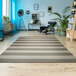 A tan and ivory striped Couristan area rug in a room with a chair and a plant.