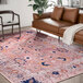 A pink and beige Abani Molana Collection area rug in a room with a brown couch and chair