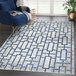 A blue and gray Abani Atlas Collection area rug with white and blue geometric designs in a room.