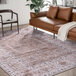 A brown and beige Abani Molana Collection area rug under a brown couch and chair