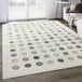 A cream and gray area rug with gray dots and circles.