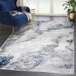 An Abani Atlas Collection gray contemporary abstract area rug with blue and white marble designs in a room.