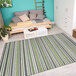 A Couristan Cape Brockton hunter green and brown striped runner rug in a room with a bed.