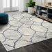 An Abani Arto Collection cream and gray geometric trellis area rug in a room with a white pot and green leaves.