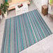 A Couristan Cape Brockton area rug with blue and white stripes on the floor in a room.