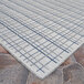 A Couristan area rug with an ivory and blue check pattern on a white background.