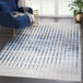 An Abani Atlas Collection blue and gray rug with vertical lines in a white room.