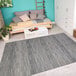 A room with a Couristan silver and charcoal area rug under a bed.