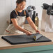 A woman cutting black Lavex tissue paper on a table.