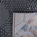 A black and white Couristan Afuera Anode area rug with geometric patterns on a stone surface.