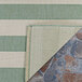 A Couristan Afuera Yacht Club sea mist and ivory striped rug on a stone floor.