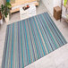 A Couristan Cape Brockton Cobalt and Teal striped rug on the floor in a room with a table and a mug.