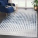 An Abani Atlas Collection blue and gray area rug with vertical lines in a room with a blue chair.