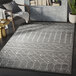 A gray and cream Moroccan trellis area rug with geometric patterns in a room.