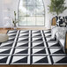 An Abani Parker Collection cream and black geometric area rug with high-contrast squares on a floor in a room with a couch.