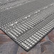 A Couristan Everhome area rug in charcoal and ivory with geometric designs on a stone surface.