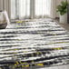 An Abani Arto Collection yellow and gray contemporary area rug with distressed stripes in a room with a white blanket.