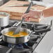 A person using a Vollrath saute pan with a spatula to cook.