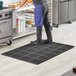 A man standing on a black Lavex anti-fatigue floor mat in a kitchen.