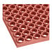 A close up of a red rubber anti-fatigue floor mat with holes in it.