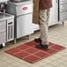 A person standing on a red Lavex anti-fatigue floor mat.