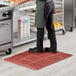 A man standing on a red Lavex anti-fatigue floor mat in a kitchen.