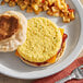 A white plate with a breakfast sandwich made with a Papetti's scrambled egg patty and a side of potatoes.