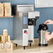 A person pouring coffee into a black and silver coffee machine.