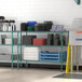 A Regency green wire shelving unit in a school kitchen with various items on the shelves.