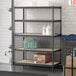 A Lavex black steel upright for boltless shelving units on a shelf with bottles and boxes.