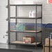 A Lavex black boltless shelving unit with shelves holding bottles and a box.