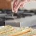 A person's hand sprinkling Regal Organic Granulated Garlic on bread.