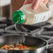 A person pouring Regal Organic Onion Powder into a pan of food.