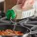 A person pouring Regal Organic Granulated Onion into a pan of food.