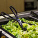 A black plastic Fineline salad tong serving a salad.