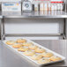 A Carlisle pearl white fiberglass market tray holding cookies on a table.