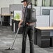 A man using a Hoover cordless backpack vacuum to clean a floor in an office.