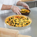 A person in gloves holding a tart in a Gobel round fluted pan.