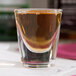 A Libbey shot glass filled with brown liquid.