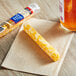 A Sargento Colby Jack cheese stick on a napkin next to a drink.