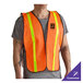 An orange high visibility mesh safety vest with 1-inch reflective tape, worn over a gray shirt.