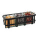 A black metal Cal-Mil condiment organizer on a table with 3 glass jars of different spices inside.