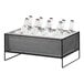 A Cal-Mil black metal ice housing with clear pan holding water bottles on a table.