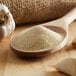 A wooden spoon filled with garlic salt next to garlic cloves.